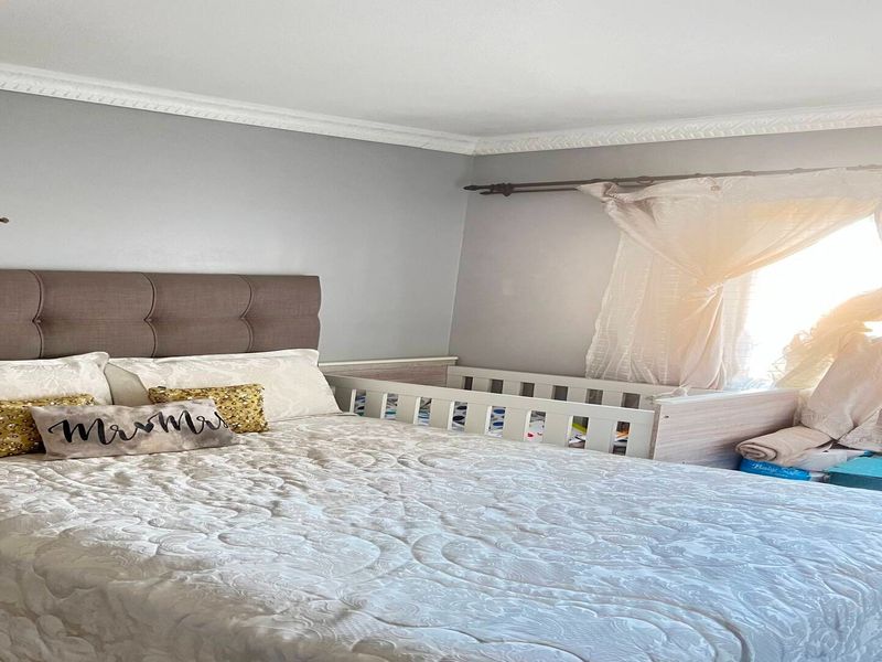 A bedroom featuring crown molding, a curtain rod, and a window with a security gate.