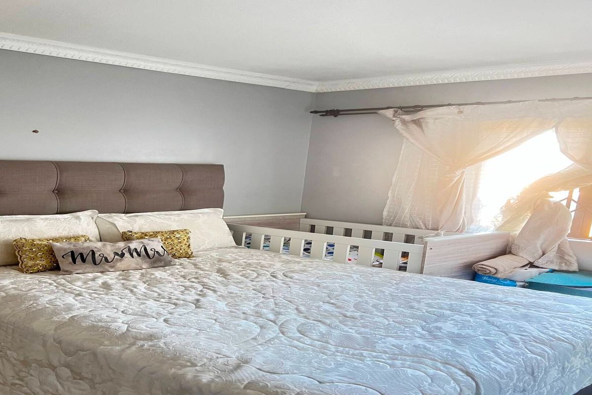 A bedroom featuring crown molding, a curtain rod, and a window with a security gate.