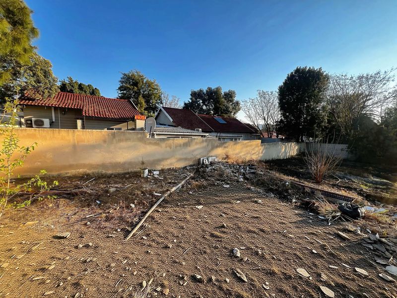 Rear yard area featuring a perimeter boundary wall and an existing swimming pool shell requiring significant clearing and landscaping.