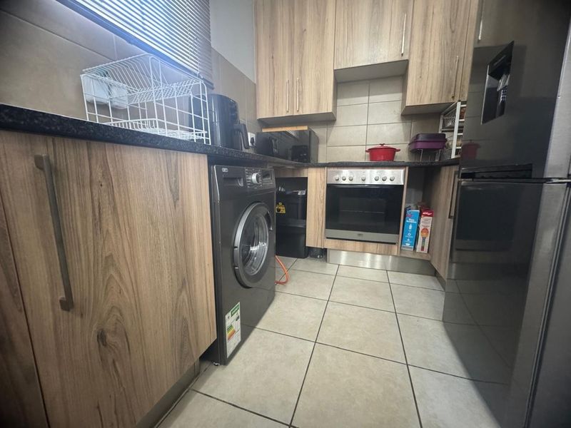 Compact kitchen featuring wood-look cabinetry, granite countertops, built-in oven, and tiled flooring with a functional layout.