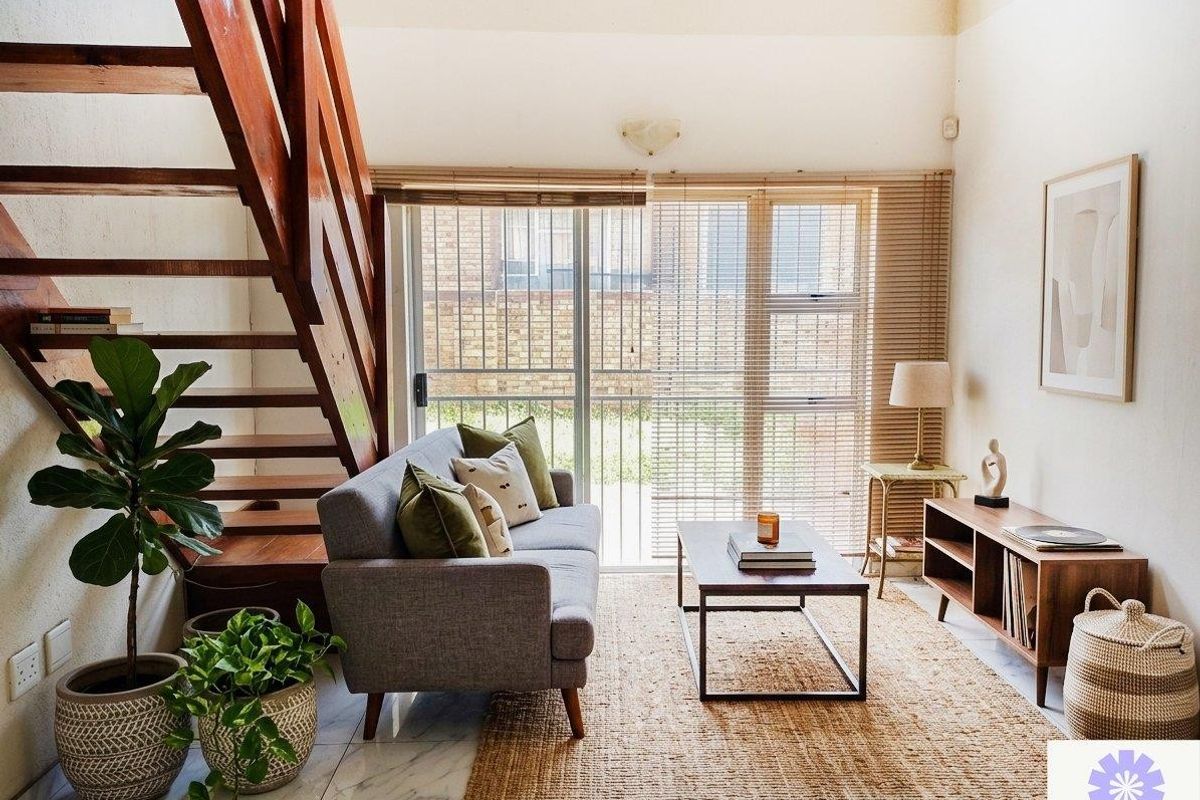 A living room featuring a wooden staircase, tiled flooring, and a sliding glass door leading to the exterior.