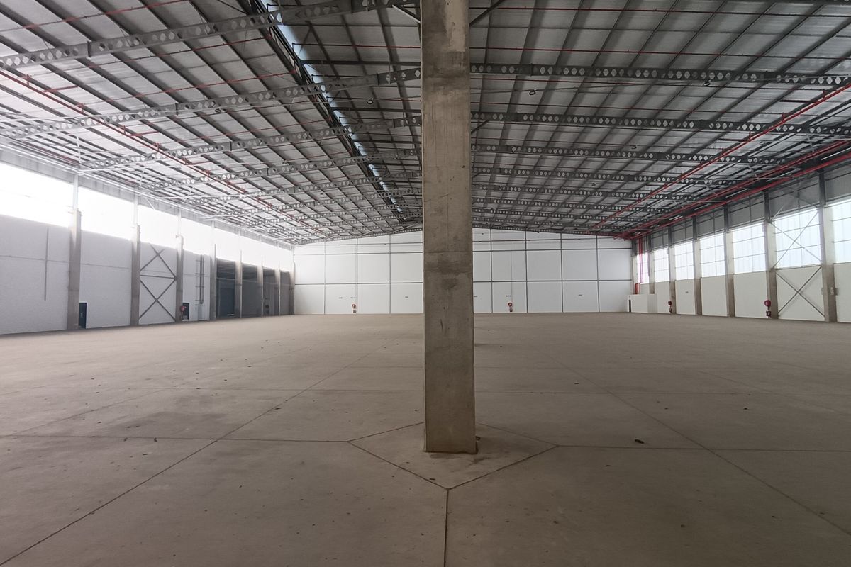 A large, open-plan industrial warehouse space featuring high ceilings, concrete flooring, and exposed steel structural elements, suitable for storage or manufacturing operations.