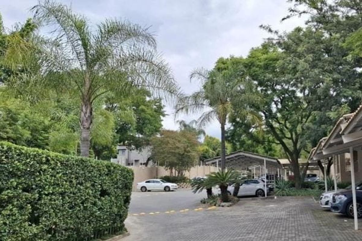Exterior view of the apartment complex featuring paved parking areas, covered carports, and established garden landscaping.