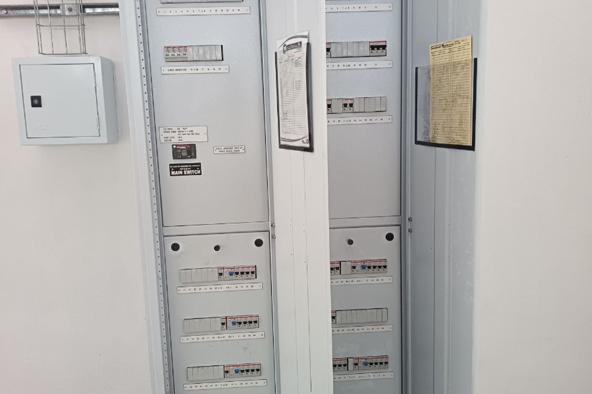 A clean, industrial-grade electrical distribution board and switchgear cabinet mounted on a wall within a warehouse utility area.