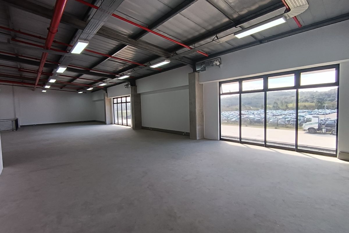 Spacious industrial utility area featuring high ceilings with exposed infrastructure, concrete flooring, and large windows providing ample natural light.