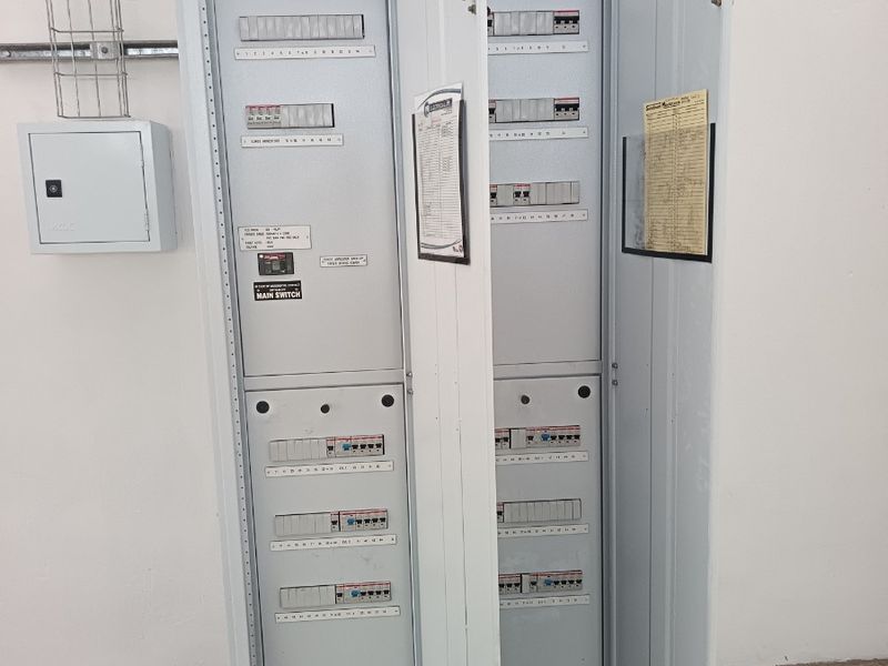 A clean, industrial-grade electrical distribution board and switchgear cabinet mounted on a wall within a warehouse utility area.