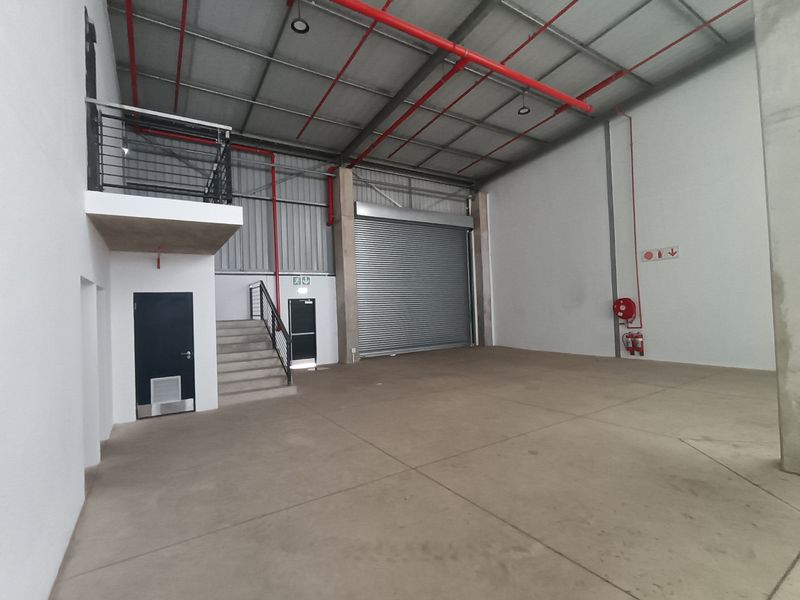 Spacious industrial warehouse unit featuring a high-clearance ceiling, roller shutter door, mezzanine level, and integrated fire safety systems.