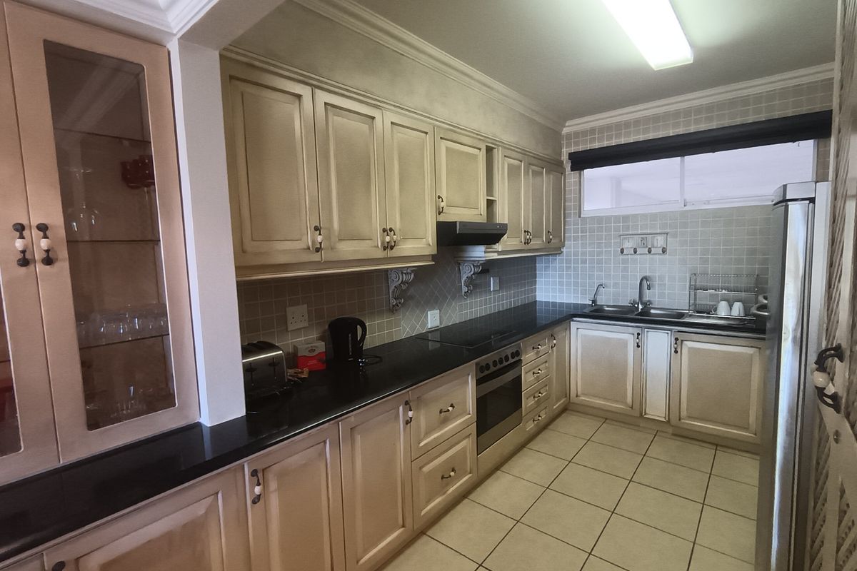 A functional kitchen featuring classic cabinetry, granite countertops, a double basin sink, built-in oven, and tiled finishes throughout.