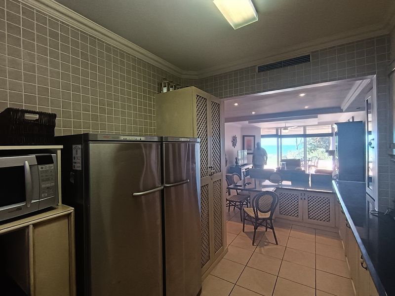Open plan kitchen and living area featuring tiled wall finishes, built-in cabinetry, and direct access to a bright living space with ocean views.