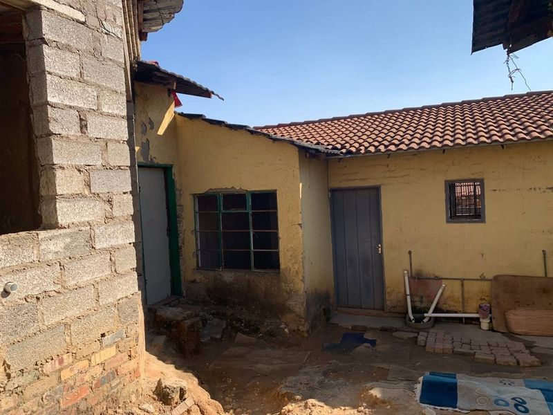 Rear exterior view of the property showing weathered plastered walls, exposed brickwork, and traditional terracotta roof tiles in need of maintenance.