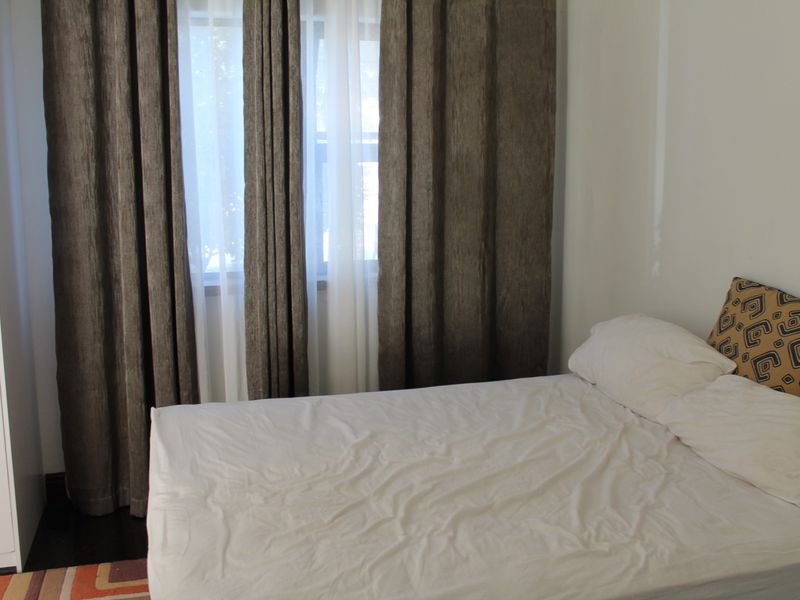 A bedroom featuring a built-in wardrobe and large window with floor-to-ceiling curtains.