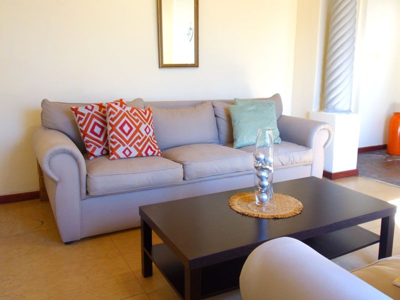 A living room area featuring tiled flooring and a decorative architectural column.