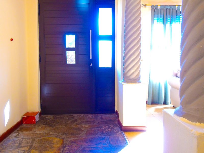 Entrance foyer featuring natural stone flooring and decorative architectural columns, leading to a solid wood front door with integrated sidelight.