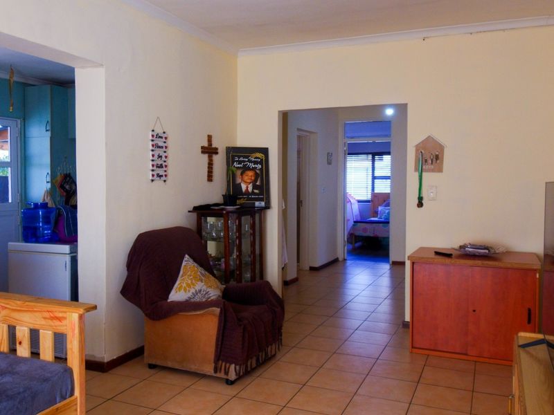 A living room area featuring tiled flooring and coved ceilings, providing access to the kitchen and hallway.