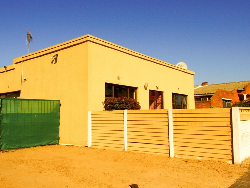 Front exterior view of a single-story house featuring a precast concrete boundary wall, security gate, and satellite dish installation.