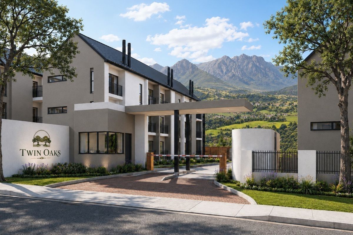 A modern apartment complex entrance featuring a secure boom gate, paved driveway, and contemporary architectural design with scenic mountain views.