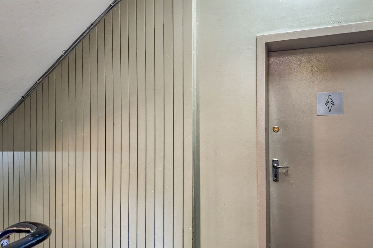 A commercial hallway featuring vertical timber wall paneling and a designated female restroom door with standard hardware.