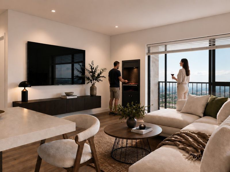 Modern open-plan living area featuring a built-in braai, sleek laminate flooring, and large sliding doors leading to a balcony with expansive views.