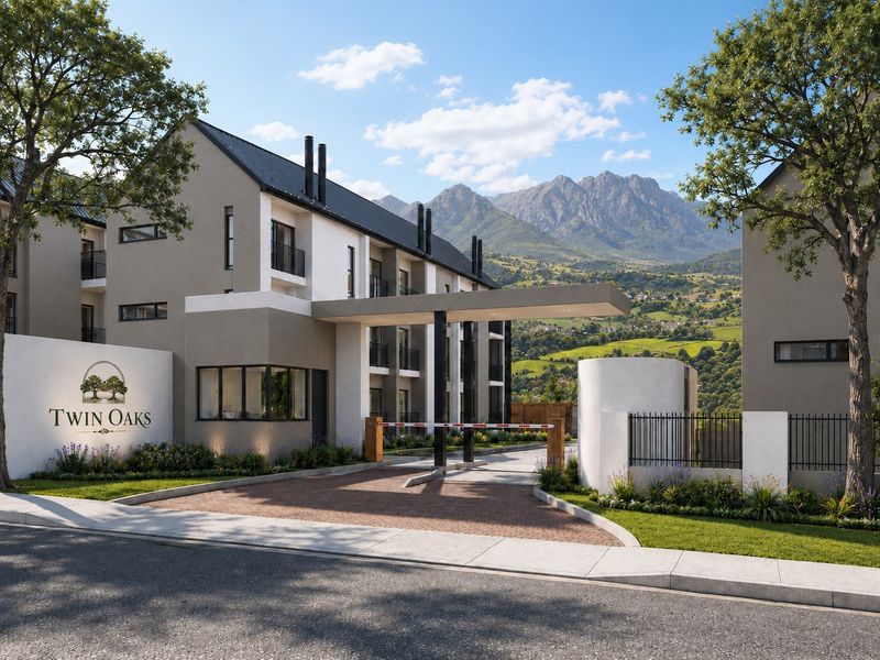 Modern apartment complex entrance featuring a secure boom gate, paved driveway, and landscaped grounds with scenic mountain views.