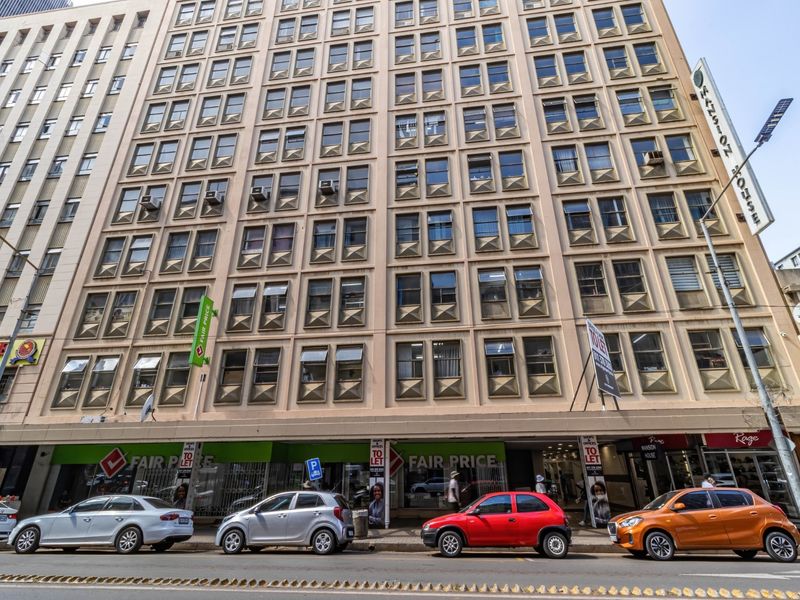 A multi-story commercial building facade featuring ground-level retail storefronts and a grid-patterned window design on the upper office levels.