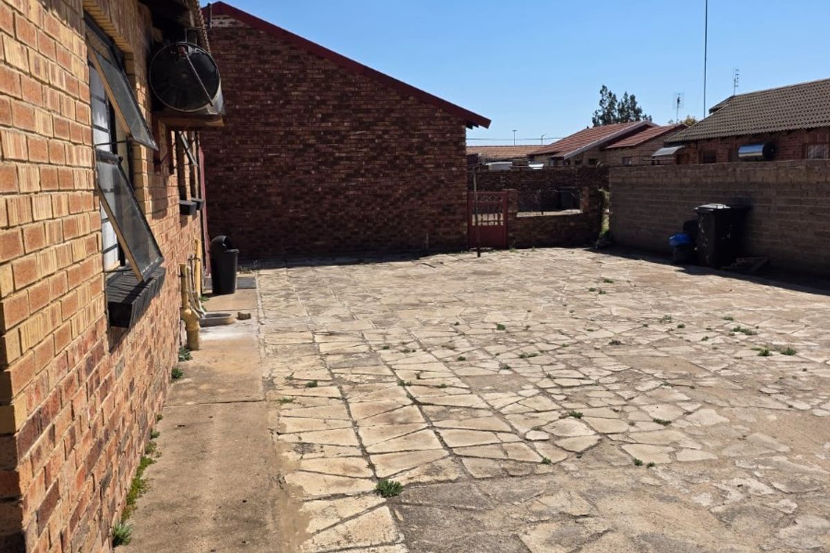 A spacious rear courtyard featuring paved flooring and face brick boundary walls, offering a functional outdoor area with potential for landscaping or patio development.