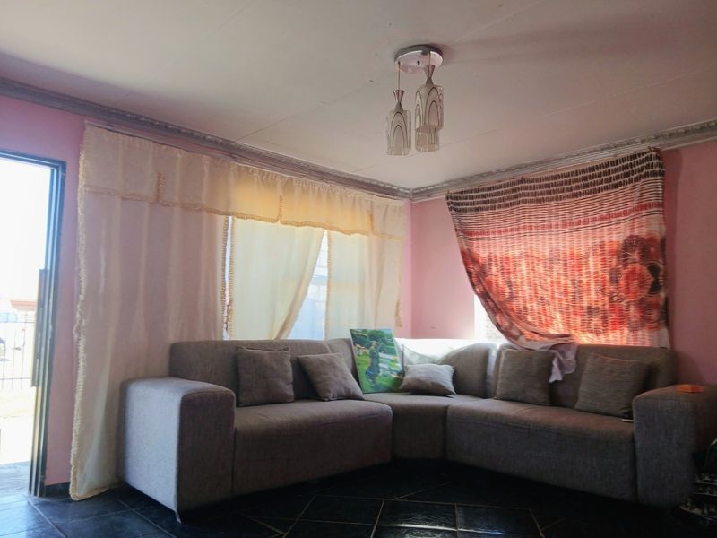 A living room featuring tiled flooring, ceiling cornicing, and a sliding glass door providing access to the exterior.