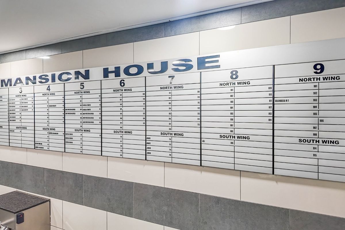 A clear and well-maintained building directory board located in the entrance area of Mansion House, displaying office suite numbers and wing locations.