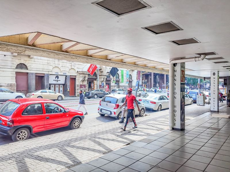 A covered commercial walkway and storefront area featuring paved flooring, structural columns, and recessed lighting, providing direct access to street-level office spaces.