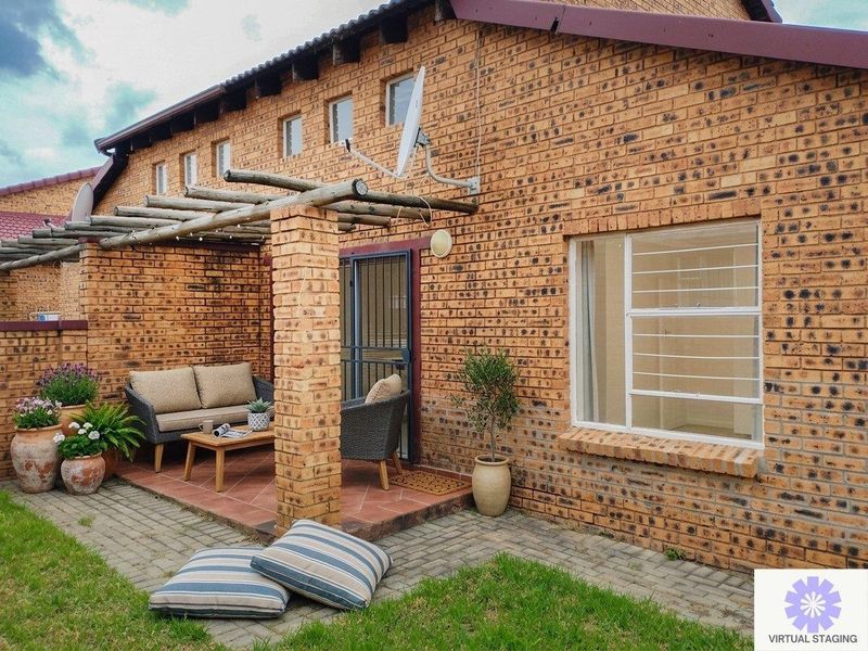 A covered patio area featuring a timber pergola, brick construction, and secure access, overlooking a small garden space.