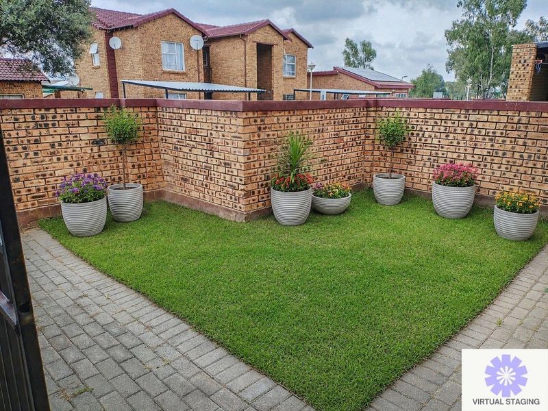 A well-maintained private garden area featuring a neat lawn, paved border, and face brick boundary wall.