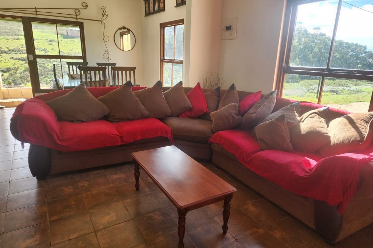A spacious living area featuring tiled flooring, large windows, and sliding glass doors that provide ample natural light and views of the surrounding landscape.