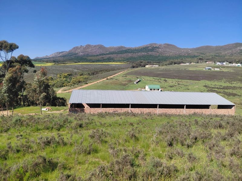 An open-sided brick structure with a corrugated metal roof set against a scenic mountain landscape.