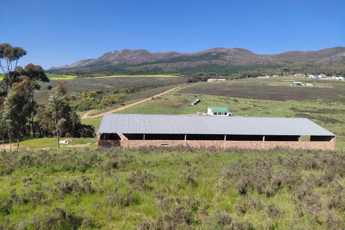 An open-sided brick structure with a corrugated metal roof set against a scenic mountain landscape.