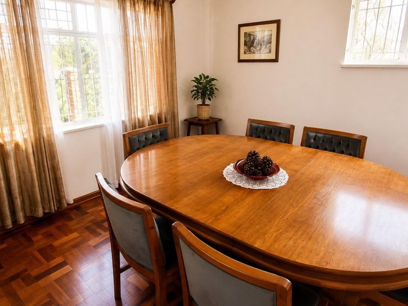 A well-maintained dining room featuring classic parquet flooring and large windows fitted with security bars, offering a bright and traditional atmosphere.
