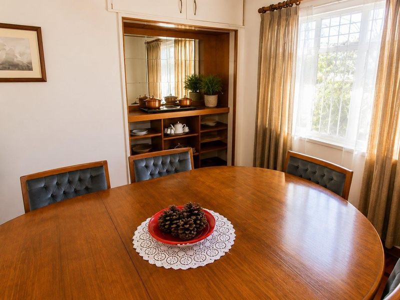 Dining room featuring parquet flooring, a window with security bars, and a built-in wooden shelving unit with a mirrored back panel.