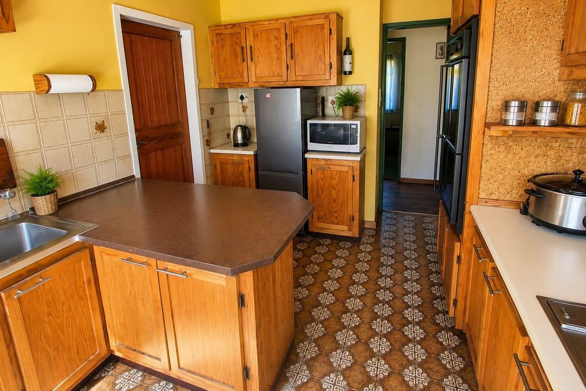 A functional kitchen featuring traditional wooden cabinetry, laminate countertops, built-in oven, and a classic tiled backsplash with patterned flooring.