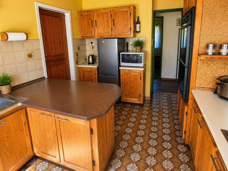 A functional kitchen featuring traditional wooden cabinetry, laminate countertops, built-in oven, and a classic tiled backsplash with patterned flooring.