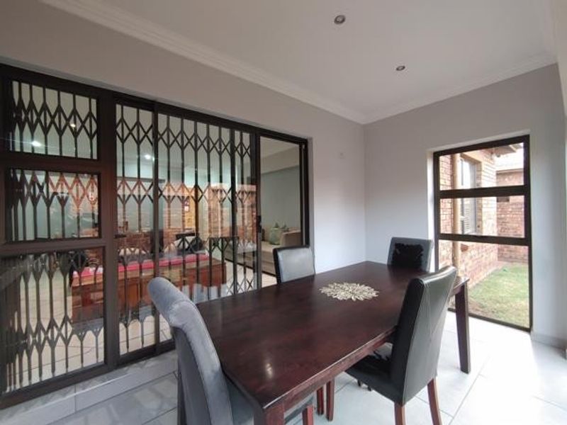 A covered patio area featuring tiled flooring, recessed lighting, and large sliding glass doors with security gates, providing access to the interior living space.