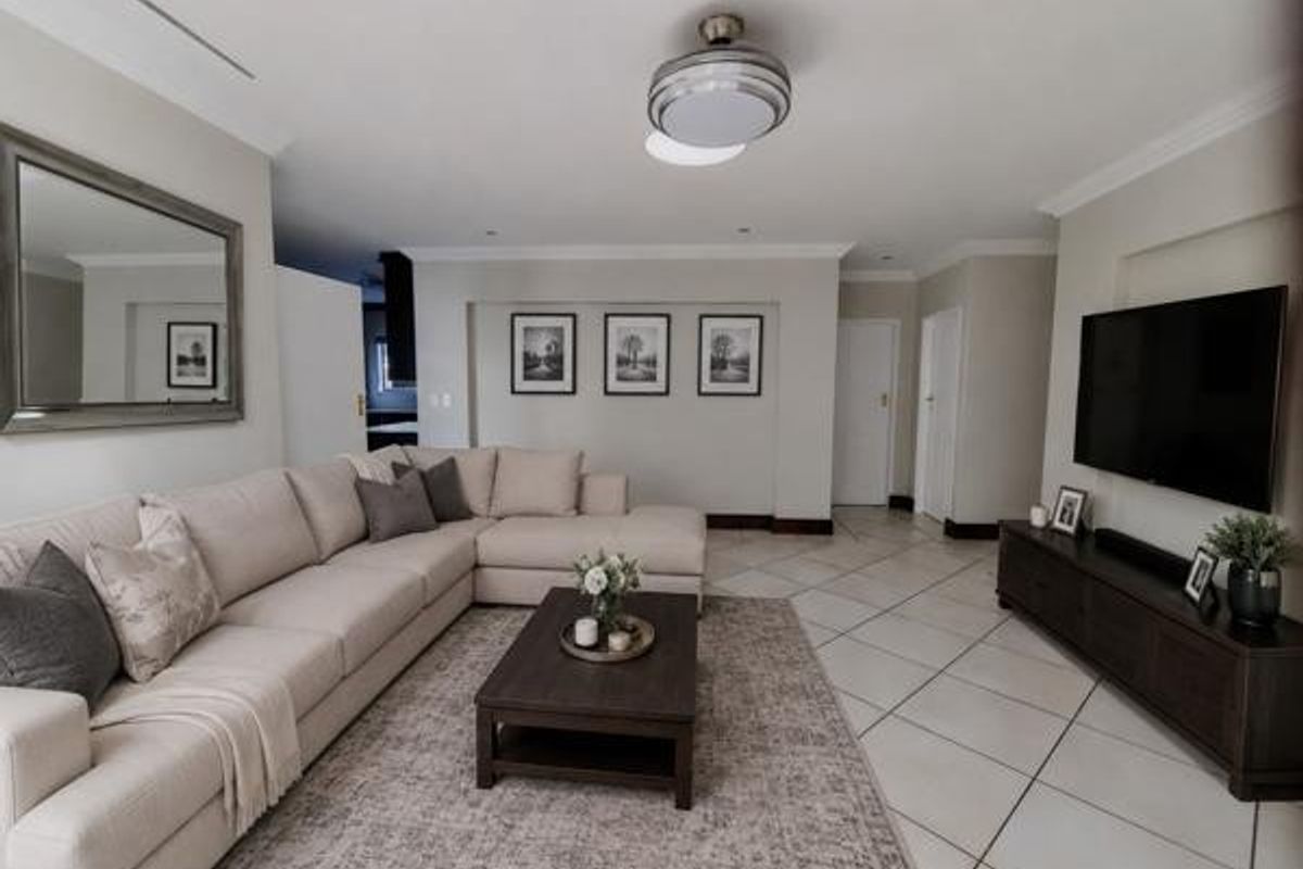 A well-maintained living room featuring neutral tiled flooring, a ceiling fan, and recessed lighting, creating a bright and comfortable living space.