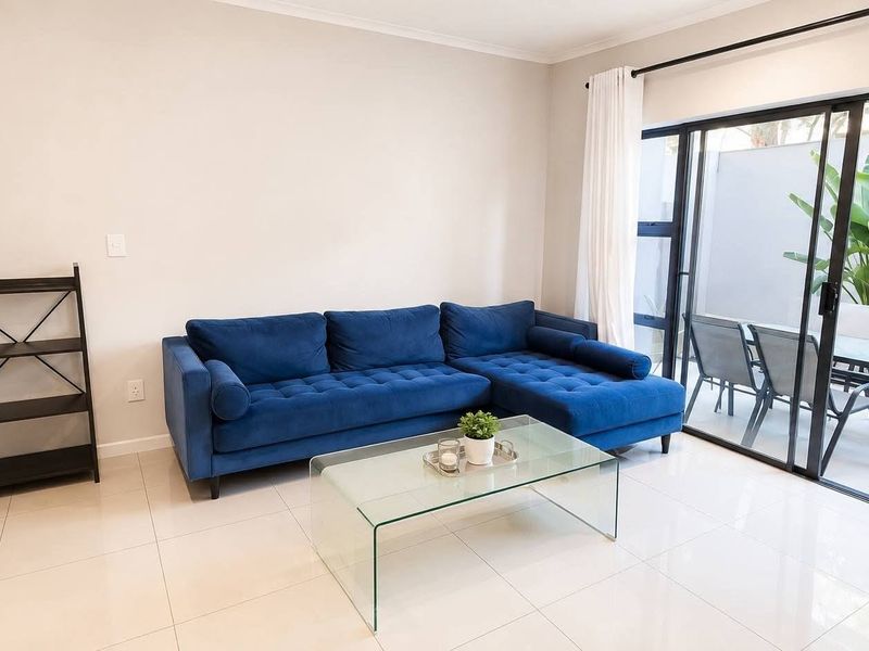 Bright living room featuring large sliding glass doors that open onto a private patio area, complemented by neutral tiled flooring.