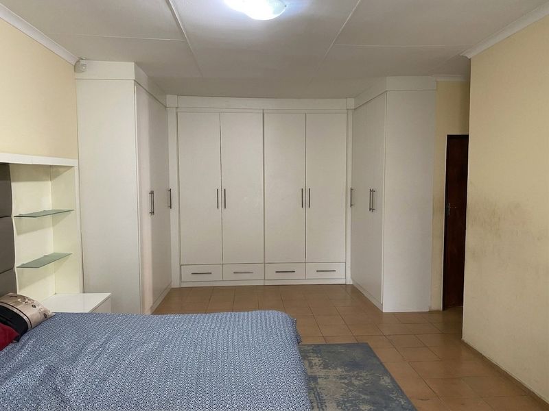 A bedroom featuring extensive white built-in cupboards, tiled flooring, and a coved ceiling.