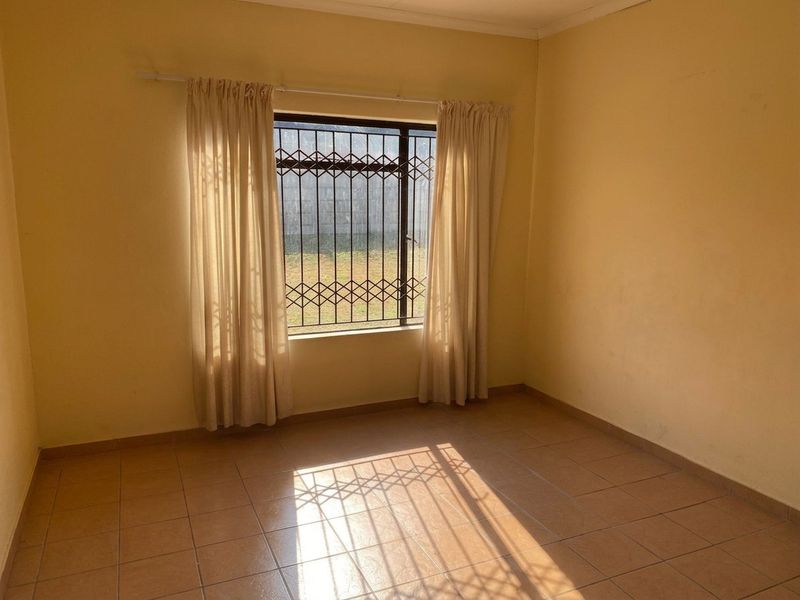 A vacant bedroom featuring tiled flooring and a window fitted with security bars, offering a neutral canvas for personalization.