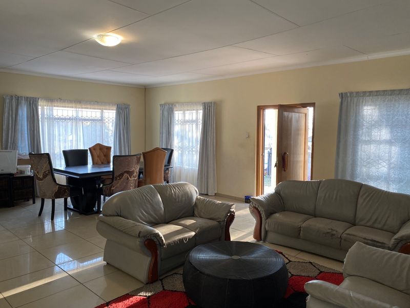 Spacious open-plan living and dining area featuring tiled flooring, natural light through multiple windows, and direct access to the exterior.