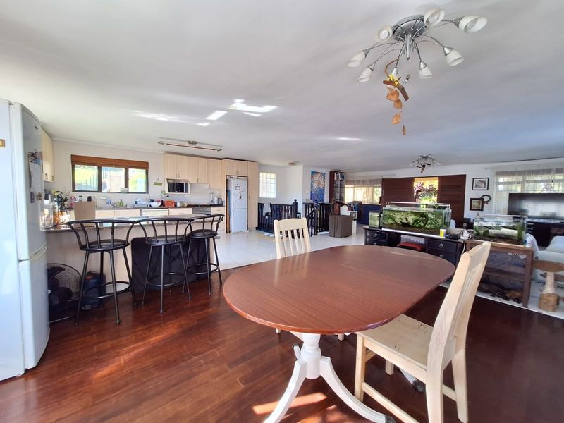 Spacious open-plan living area featuring a functional kitchen with granite countertops, hardwood flooring, and a seamless flow into the dining and lounge spaces.