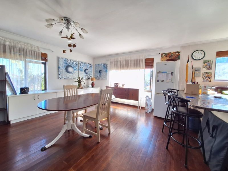 Open-plan living and dining area featuring hardwood flooring, built-in cabinetry, and a granite breakfast bar, creating a functional and connected space.