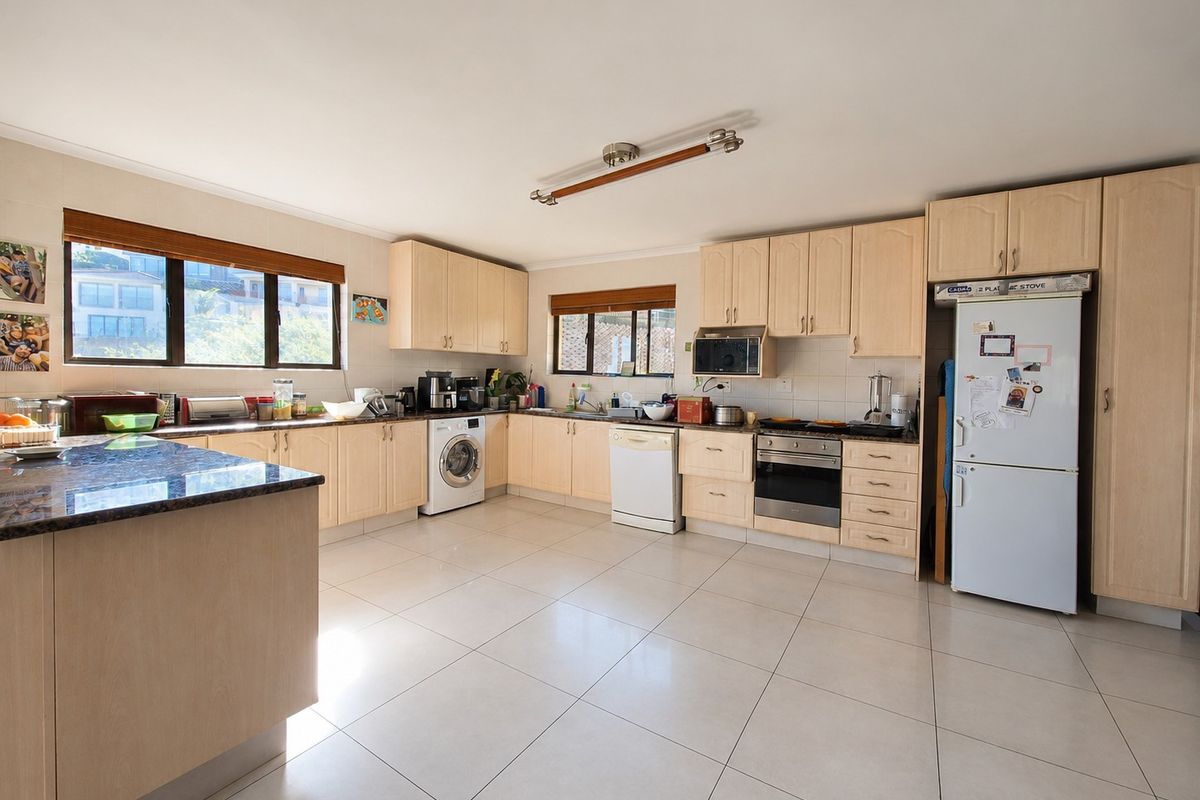 Spacious kitchen featuring light wood cabinetry, granite countertops, tiled flooring, and integrated appliances, offering a functional layout with ample storage and workspace.