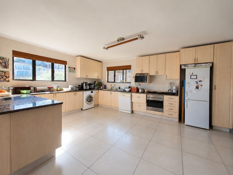 Spacious kitchen featuring light wood cabinetry, granite countertops, tiled flooring, and integrated appliances, offering a functional layout with ample storage and workspace.