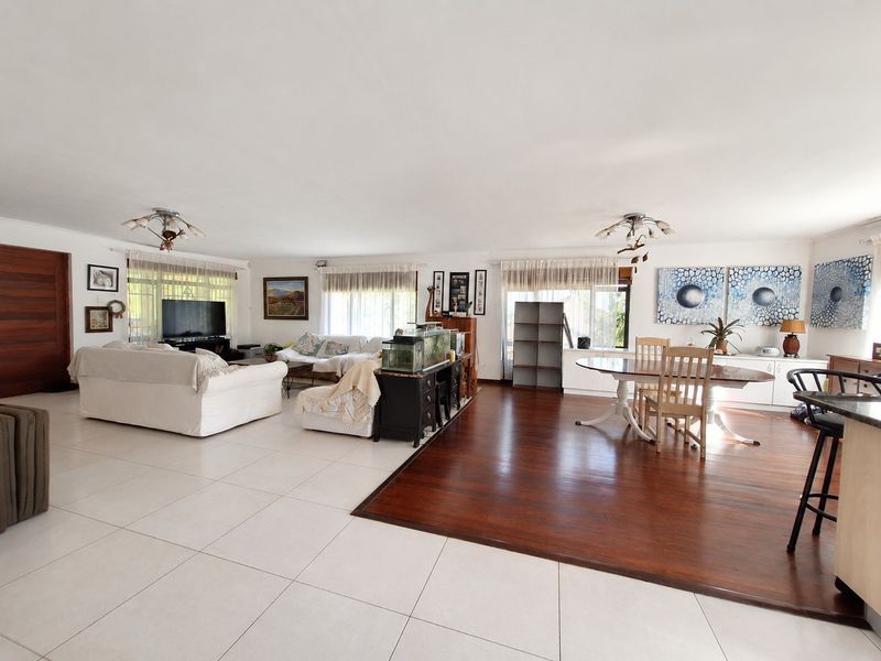 Spacious open-plan living and dining area featuring a combination of tiled and hardwood flooring, neutral walls, and integrated cabinetry.