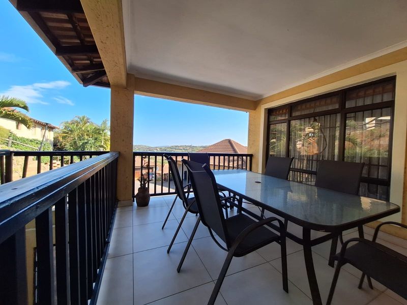 A covered balcony featuring tiled flooring, a metal balustrade, and large glass sliding doors, offering an outdoor space with scenic views.