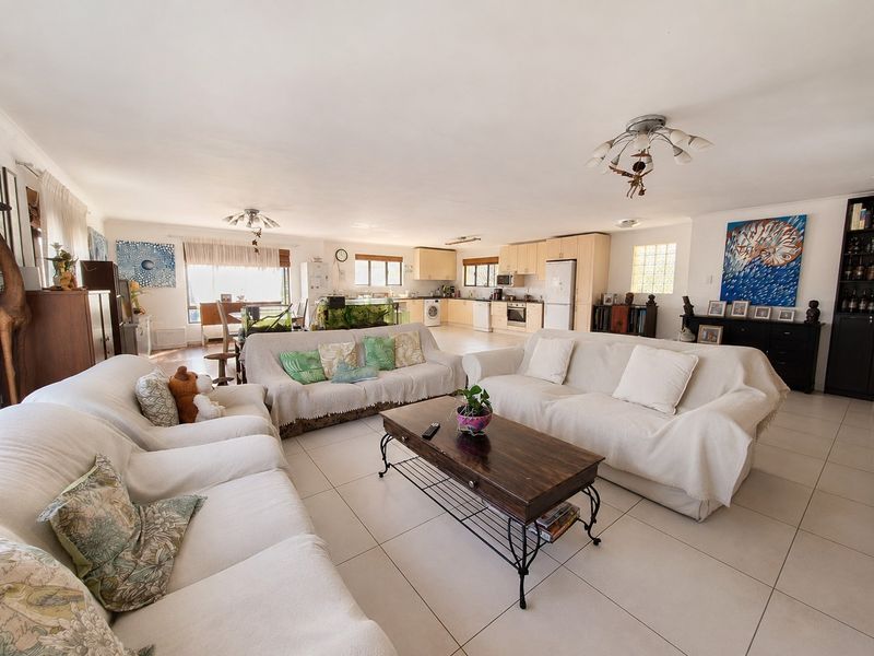 Spacious open-plan living area featuring tiled floors and a functional kitchen with built-in cabinetry, oven, and hob, creating a versatile family living space.